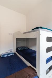 Casa nova condomínio fechado Praia Grande SP في Solemar: سريرين بطابقين في غرفة بيضاء مع سرير