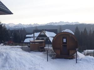 ein Hobbyhaus im Schnee vor einem Haus in der Unterkunft Tybet Domki i Apartamenty in Bukowina Tatrzańska