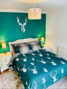 a bedroom with a blue bed and a green wall at Gorwel, Spacious 3 Bedroom Cottage near the Beach in Llanarth