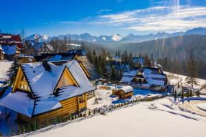 eine Luftansicht eines verschneiten Dorfes in den Bergen in der Unterkunft Tybet Domki i Apartamenty in Bukowina Tatrzańska