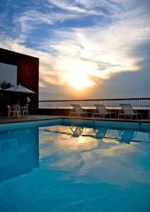 薩爾瓦多的住宿－SOL VICTORIA MARINA，一个带桌椅的游泳池,享有日落美景