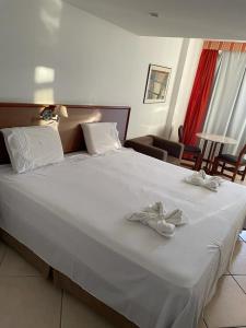 uma grande cama branca com duas toalhas brancas em SOL VICTORIA MARINA em Salvador