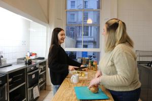 dwie kobiety stojące w kuchni rozmawiające w obiekcie Urbany Hostel London 18-40 Years Old w Londynie