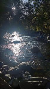 un río con rocas y el sol reflejándose en el agua en Cabaña Río Iculpe, en Lago Ranco