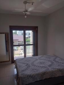 a bedroom with a bed and a large window at Duplex novo in Tramandaí