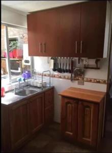 una cucina con armadi in legno, lavandino e finestra di Casa Verano Dichato a Dichato
