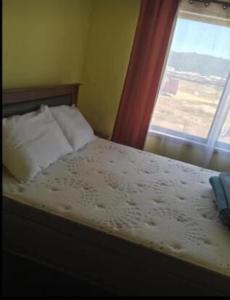 una camera con un letto con una finestra e un copriletto di Casa Verano Dichato a Dichato