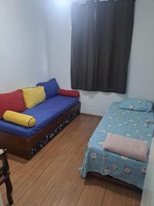 a living room with a couch and a bed at Margaça Condomínio Califórnia in Rio de Janeiro
