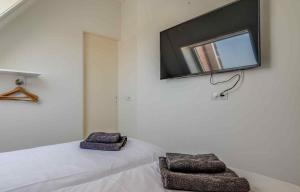 a bedroom with two beds and a flat screen tv on the wall at Vakantiewoning Scheldestraat 23 Zoutelande, dicht bij Domburg in Zoutelande