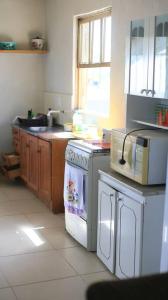 uma cozinha com um fogão branco forno superior ao lado de uma janela em Casa de praia - Descanse e tenha uma experiencia relaxante a poucos metros da praia em Arroio do Silva