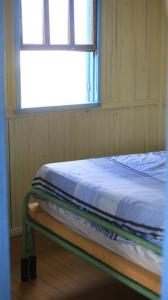 Bett in einem Zimmer mit Fenster in der Unterkunft Casa de praia - Descanse e tenha uma experiencia relaxante a poucos metros da praia in Arroio do Silva