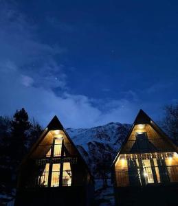 une cabane en rondins éclairée dans la neige dans l'établissement Cottage Paradise, à Kazbegi