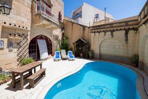 een zwembad op een binnenplaats met 2 stoelen en een bank bij 3 Bedroom Farmhouse with Private Pool in Zebbug Gozo in Żebbuġ