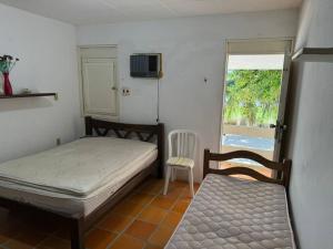 ein Schlafzimmer mit einem Bett und einem Stuhl und einem Fenster in der Unterkunft Casa Pê na Areia e Vista ao Mar em São José in São José da Coroa Grande
