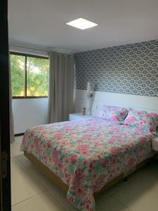 1 dormitorio con 1 cama grande con colcha de flores en Barra Bali Beach Service 323 BARRA DE SÃO MIGUEL, en Barra de São Miguel