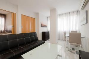 un soggiorno con divano nero e tavolo di PRECIOSO y ACOGEDOR APARTAMENTO EN GRANADA a Granada