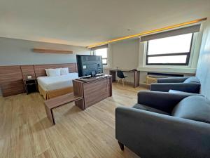 een hotelkamer met een bed, een tv en een bank bij Hotel El Sembrador in Guasave