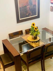 a glass table with a vase with a sunflower on it at Triplex c/ hidro 15 min do Praia de Belas e Barra Shopping in Porto Alegre