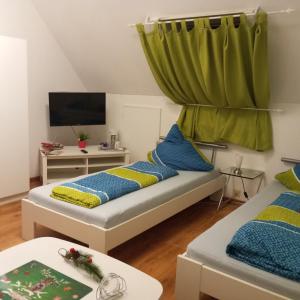 ゾーリンゲンにあるGäste Monteurzimmer Haus Südstadtのベッド2台とテレビが備わる小さな客室です。