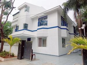 una casa blanca con acentos azules en Bay Breeze Suites, en Chennai