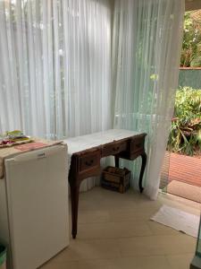 uma mesa de madeira em frente a uma janela com cortinas em Pouso Costa do Sol em Bertioga