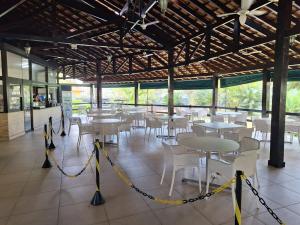a restaurant with tables and chairs and a yellow rope at PARAÍSO Ubatuba - Praia Grande-Toninhas - Apartamento Cond Wembley Tenis in Ubatuba