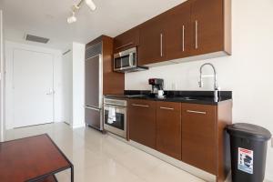 a kitchen with wooden cabinets and a sink and a table at Icon Brickell W Residences in Miami