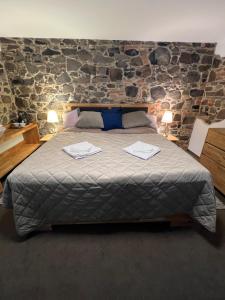 a bedroom with a large bed with a stone wall at ŠTAJNHAUS DUBICE in Řehlovice +29 photos