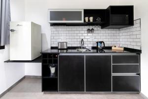 a kitchen with black cabinets and a white refrigerator at El Refugio Apart in Villa Serranita