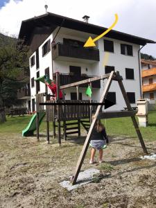 ein kleines Mädchen auf einer Schaukel auf einem Spielplatz in der Unterkunft Carè Alto in Carisolo