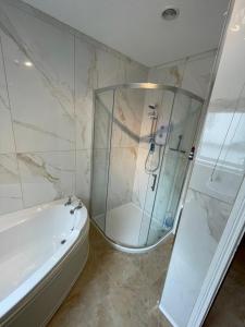 a bathroom with a shower and a tub and a sink at Tranquility Portstewart in Portstewart