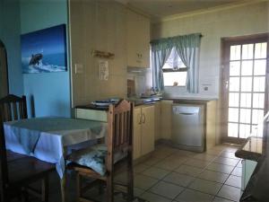 uma cozinha com uma mesa e uma cozinha com um lavatório em Scottburgh beach house em Scottburgh