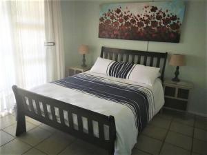 uma cama num quarto com dois candeeiros e um quadro em Scottburgh beach house em Scottburgh
