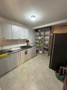 uma cozinha com armários brancos e um frigorífico preto em Cabaña Quindiana - Excelente Ubicación em Montenegro