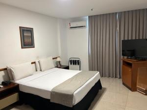 um quarto de hotel com uma cama e uma televisão de ecrã plano em Américas Benidorm Hotel no Rio de Janeiro