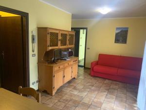 ein Wohnzimmer mit einem roten Sofa und einem TV in der Unterkunft Carè Alto in Carisolo