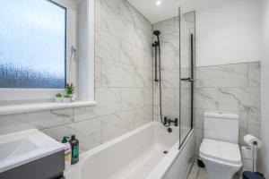 y baño con bañera, aseo y lavamanos. en Modern 4 Bed House-Free Parking, en Uphall