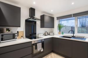 a kitchen with black and white appliances and a window at Modern 4 Bed House-Free Parking in Uphall