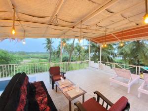 a patio with chairs and tables on a balcony at sea shore guest house morjim beach in Morjim