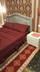 a bed with a red comforter and a night stand at La Casa di Sonia in Savona