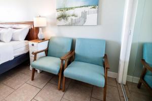 Dos sillas en una habitación con una cama y una lámpara. en Majestic Seascape 6th Flr Oceanfront King Room, en Pawleys Island