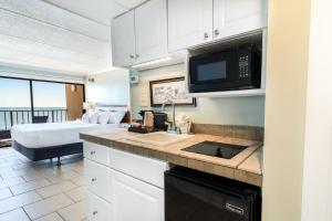 Una cocina con fregadero y una cama en una habitación. en Majestic Seascape 6th Flr Oceanfront King Room, en Pawleys Island