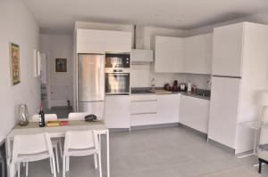 eine Küche mit weißen Schränken sowie einem Tisch und Stühlen in der Unterkunft Valinor Apartments Boliches in Fuengirola