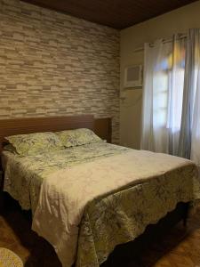 Un dormitorio con una cama y una pared de ladrillo. en Flavia Aluguel Temporada, en Cabo Frío 8 fotos más