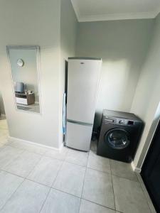 a kitchen with a refrigerator and a washing machine at Ice Holiday Home in Kiddʼs Beach