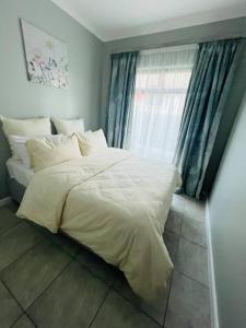 a bedroom with a white bed and a window at Ice Holiday Home in Kiddʼs Beach
