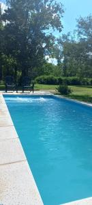 een blauw zwembad met twee banken in een park bij La Cabañita in Colonia Caroya