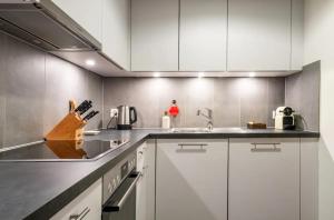 uma cozinha com armários brancos e um lavatório em Stylish Lakeside Home by the Jet d'Eau em Genebra