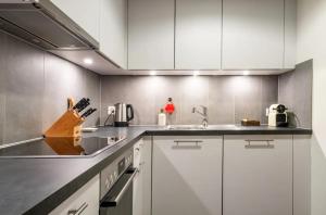 a kitchen with white cabinets and a sink at Stylish Lakeside Home by the Jet d'Eau in Geneva