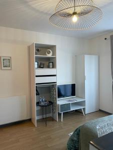 a living room with a bed and a desk with a television at Le jardin de Broceliande in Ploërmel